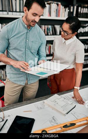 Man, woman and notebook for architecture in office with model, design or blueprint for property expansion. People, reading and check for floor plan Stock Photo