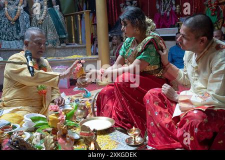 A pregnant Hindu pandita & her husband & their pandit at a Valaikappu service in Queens, NY, in 2024. It'a the equivalent of a baby shower. Stock Photo