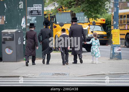 A view from behind of a Hasidic father & 4 children walking south on away in Williamsburg, Brooklyn, New York. Stock Photo