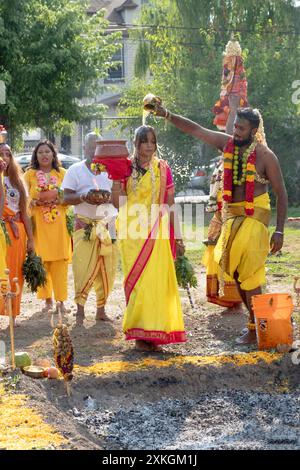Prior to her Thimithi walk on hot burning coals, a Hindu woman has a liquid poured over her head. At the Arya Spiritual grounds in Jamaica NYC. Stock Photo