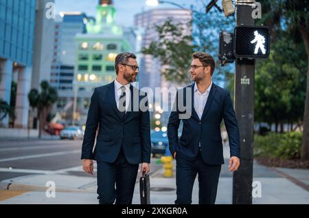 Business people discuss a project. Two young businessmen outdoors city looking cityscape. Businessmen communicating at meeting. Meeting of two Stock Photo