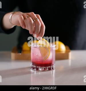 A woman's hand is preparing a refreshing summer beverage. Iced drink cocktail. Stock Photo