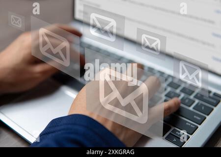 A hand typing on a laptop with several email inbox icons. Email spam, digital newsletter concept. Stock Photo