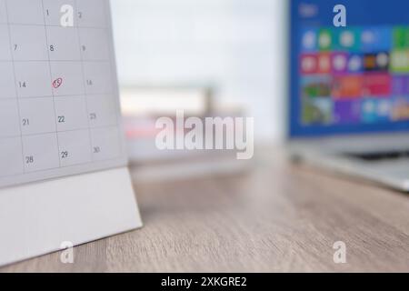 A desk calendar on a wooden table with a red circle marking a specific date. Appointment and reminder concept. Stock Photo