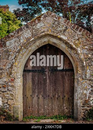 Old double wooden door in stone wall at Bosham, West Sussex, UK Stock Photo