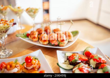 Close-up of delicious snacks on a wooden table in the dining room at home. Tasty hearty dishes. Sausage and cheese slicing with olives and tomatoes. S Stock Photo