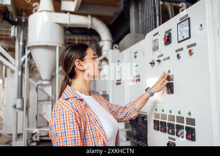 A young woman works at an elevator. An attractive female agronomist adjusts the machinery. The grain processing technician checks the equipment. The o Stock Photo