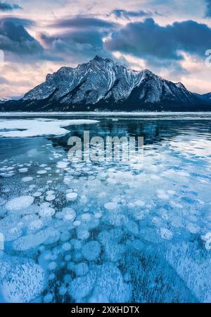 Landscape of natural bubbles frost on frozen Abraham Lake with rocky mountains in winter at Kootenay Plains Area, Alberta, Canada Stock Photo