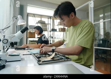 Colleagues Repairing Laptops In Workshop Stock Photo