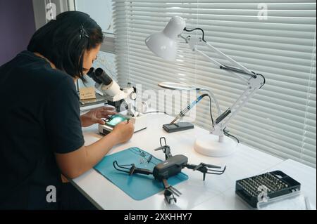 Master Examining Details Of Drone In Microscope Stock Photo