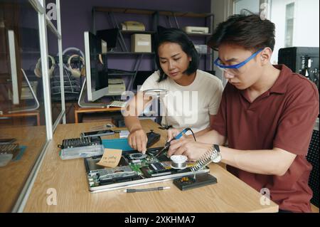 Colleagues Repairing Laptop Together In Workshop Stock Photo