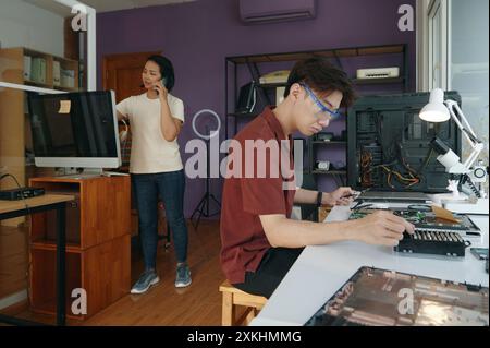 People Working With Broken Computers In Workshop Stock Photo