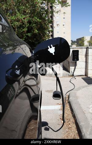 Black electric car is being charged at contemporary ev charging station ...