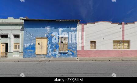 539 One-storey Colonial house of very chipped blue facade between two Eclectic buildings on Santa Rita Street north-uneven numbers side. Santiago-Cuba Stock Photo