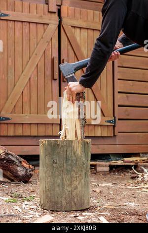 Hands and axe in firewood, man chopping wood for fire heat, preparing firewood for winter in summer season Stock Photo