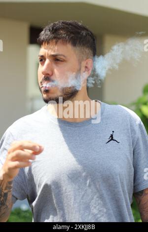 A vivid image featuring a young man smoking a joint on a sunny day in the city of Zurich. Ideal for themes related to urban culture, relaxation, and l Stock Photo