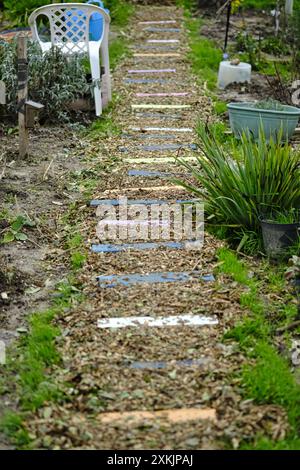 Pallet wood upcycled into painted wooden stepping stones on a woodchip path Stock Photo