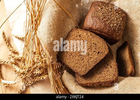 Sliced village rye bread Borodinsky in a wicker basket on canvas fabric with ears of rye. High quality photo Stock Photo