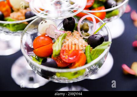 A close-up of fresh vegetable salad in glass cups with tomatoes and olives. Stock Photo