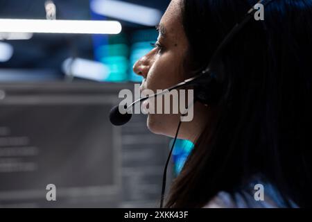 Data center operator assisting project teams with complex installations, issuing commands though headset mic. Expert in server hub communicating with engineers in remote call, close up Stock Photo