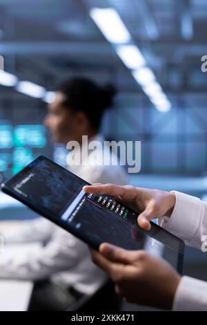 Computer scientist using tablet, optimizing data center performance. Close up of IT professional using device to troubleshoot mainframes, ensuring optimal performance and minimizing downtime Stock Photo