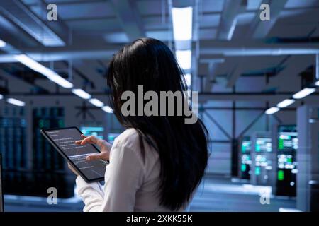 Admin in data center using tablet to check for server performance issues arising due to high CPU usage. Server room employee fixing insufficient memory errors slowing down hardware Stock Photo