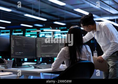 Teamworking technicians in server room looking to find network issues affecting supercomputer performance. IT experts fixing slow data transfer rates in data center equipment Stock Photo