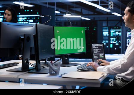 IT operators in data center checking equipment performance on isolated screen computer after upgrading infrastructure. Admins doing maintenance on supercomputers in servers room using chroma key PC Stock Photo