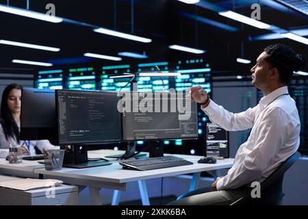 System administrator looking at holograms in data center, monitoring equipment. IT staff member in server farm interacting with futuristic augmented reality AI visualization Stock Photo