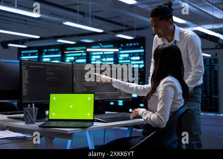 Team of technicians using mockup laptop to check server clusters configuration settings. Teamworking experts checking event logs in monitoring software to find faulty data center hardware root cause Stock Photo