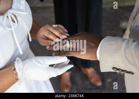 Newly married bride places wedding ring on the black finger of her husband hand during ceremony. Stock Photo