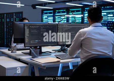 Technician using computer to troubleshoot hardware and software issues in server hub. IT expert implementing and maintaining server and network infrastructure in data center using PC Stock Photo
