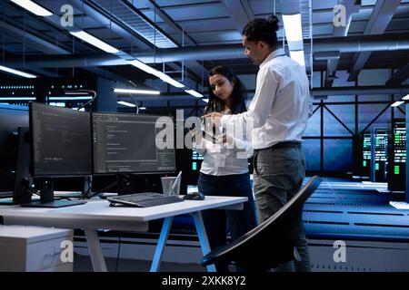 Tablet used by team of programmers in server room to find network issues affecting supercomputer performance. IT staff members fixing slow data transfer rates in data center Stock Photo