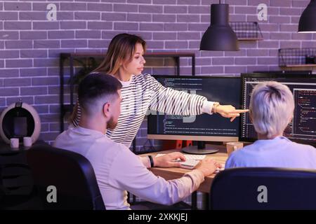 Female programmer with her colleagues working in office at night Stock Photo