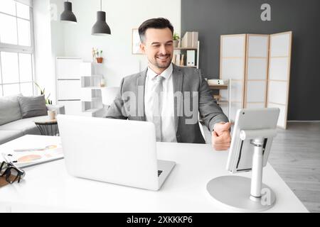 Young businessman unlocking tablet computer at table in office Stock Photo