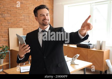 Young businessman with tablet computer using virtual screen in office Stock Photo