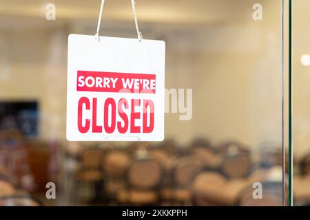 Store closed sign hanging on the window. Closed sign hanging in business window. A sign that says 'Sorry, we're closed'. close due to financial diffic Stock Photo