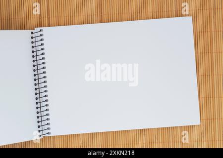 close up of blank page of sketch book laying on bamboo mat Stock Photo