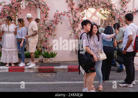 A young Chinese tourist couple at a popular photo spot in Soi Romanee (Rommani) in the Old Town area of Phuket Town, Thailand, taking selfies Stock Photo