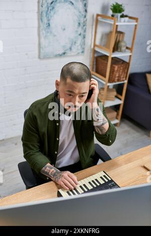 A young Asian man plays a keyboard in a recording studio, creating music. Stock Photo