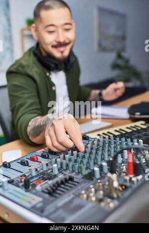 A close-up shot of a mans hand adjusting the knobs on a mixing board in a studio. Stock Photo