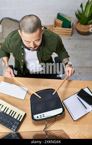 A young Asian man plays drums in a music studio. Stock Photo