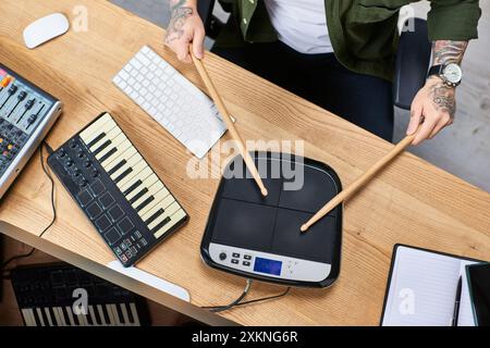 A young Asian man plays a drum pad and keyboard in his studio. Stock Photo