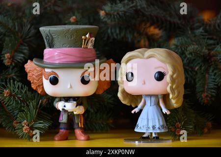 Funko Pop vinyl collection action figures of Mad Hatter and Alice in Wonderland. Fir tree branches, yellow floor, fabulous, magical Christmas. Stock Photo