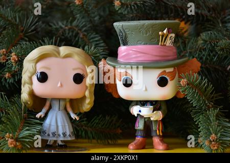 Funko Pop vinyl collection action figures of Mad Hatter and Alice in Wonderland. Fir tree branches, yellow floor, fabulous, magical Christmas. Stock Photo