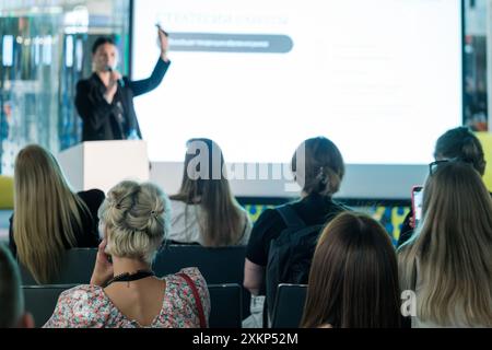 Speaker engaging with audience during business conference presentation. Attendees listening attentively and taking notes. Stock Photo