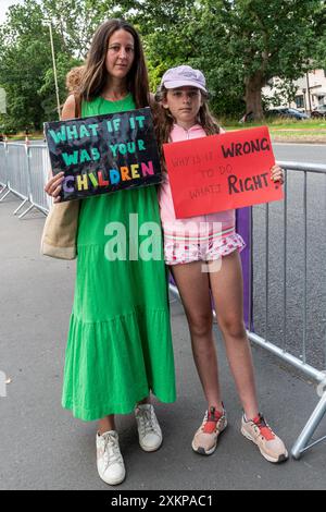 24 July 2024, Peaceful protest and vigil outside Farnborough International Airshow in Hampshire, England, UK, against the arms trade. The protesters are calling for a halt to selling weapons that are causing death and destruction in Palestine and around the world. The protest was organised by several activist groups, Greater Rushmoor Action for Peace; East Berkshire Palestine Solidarity Campaign; Quakers, and CAAT (Campaign against Arms Trade). Pictured: Mother and daughter holding anti-war placards outside the airshow grounds. Stock Photo