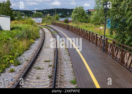 An empty railway track turning left along a station platform with yellow caution line and wooden railings Stock Photo