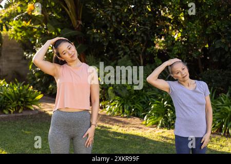 Exercising in park, asian grandmother and granddaughter stretching neck muscles outdoors together Stock Photo