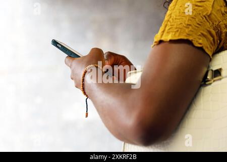 Female hands with smartphone on blurred street background. Black woman using mobile phone in city Stock Photo